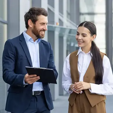 Two colleagues reviewing a tablet outside an office building.